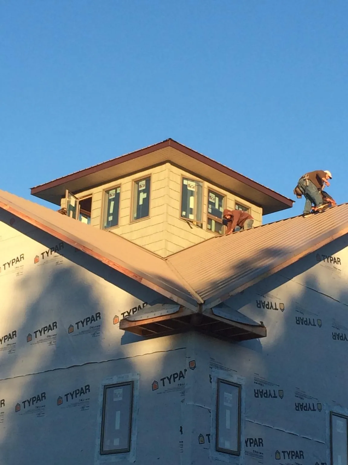 Roofers working around a rooftop cupola on a new metal roof at sunset — Roof Waterproofing in Junction City by Roofing Brothers